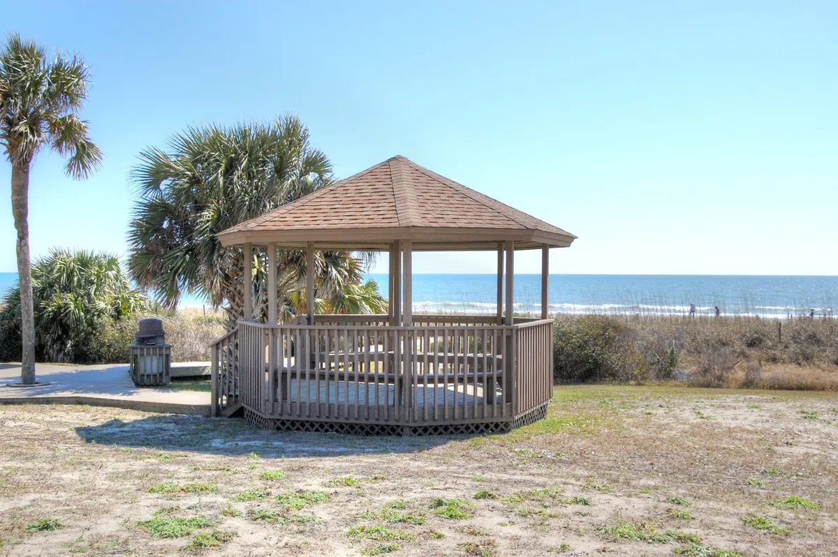An inviting gazebo overlooks the ocean, with palm trees dotting the landscape. The scene is tranquil yet brimming with vacation potential, suggesting moments of relaxation between energetic outings and excursions.