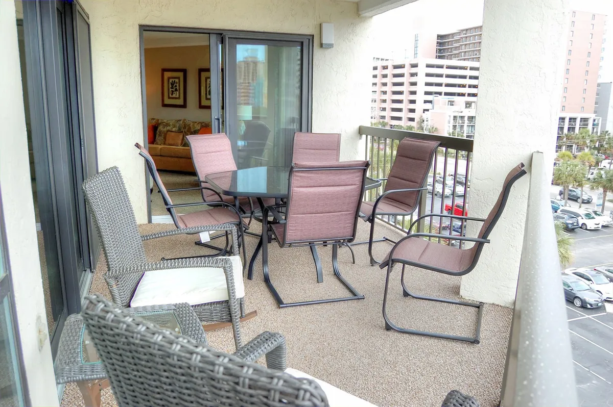 An inviting outdoor dining table and comfortable seating set the scene for alfresco dining or socializing, with a view of the surrounding area. The setting suggests both morning and evening enjoyment, complementing the idea of soaking in the coastal breeze and making memories outdoors.